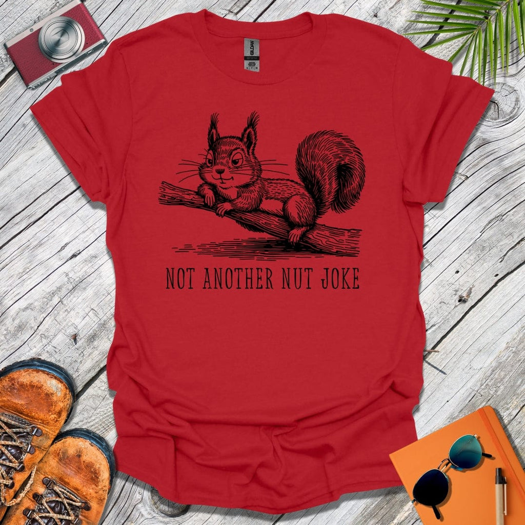 Red t-shirt with a squirrel graphic and text 'Not Another Nut Joke' on a wooden surface.