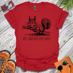 Red t-shirt with a squirrel graphic and text 'Not Another Nut Joke' on a wooden surface.